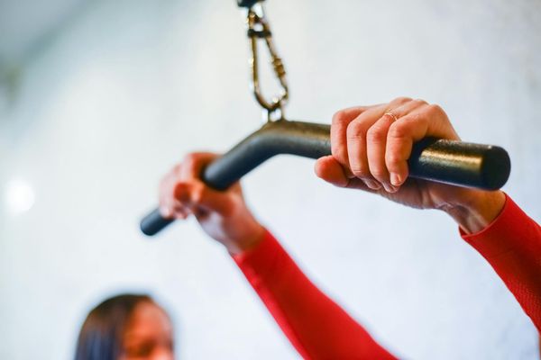 Close-up of a man's hands gripping a pull-up bar, muscles tensed.